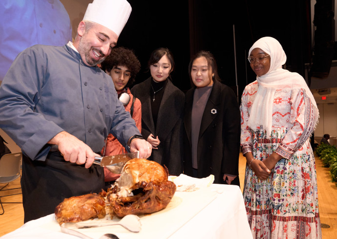 Joe Sidoni carves a turkey while students look on