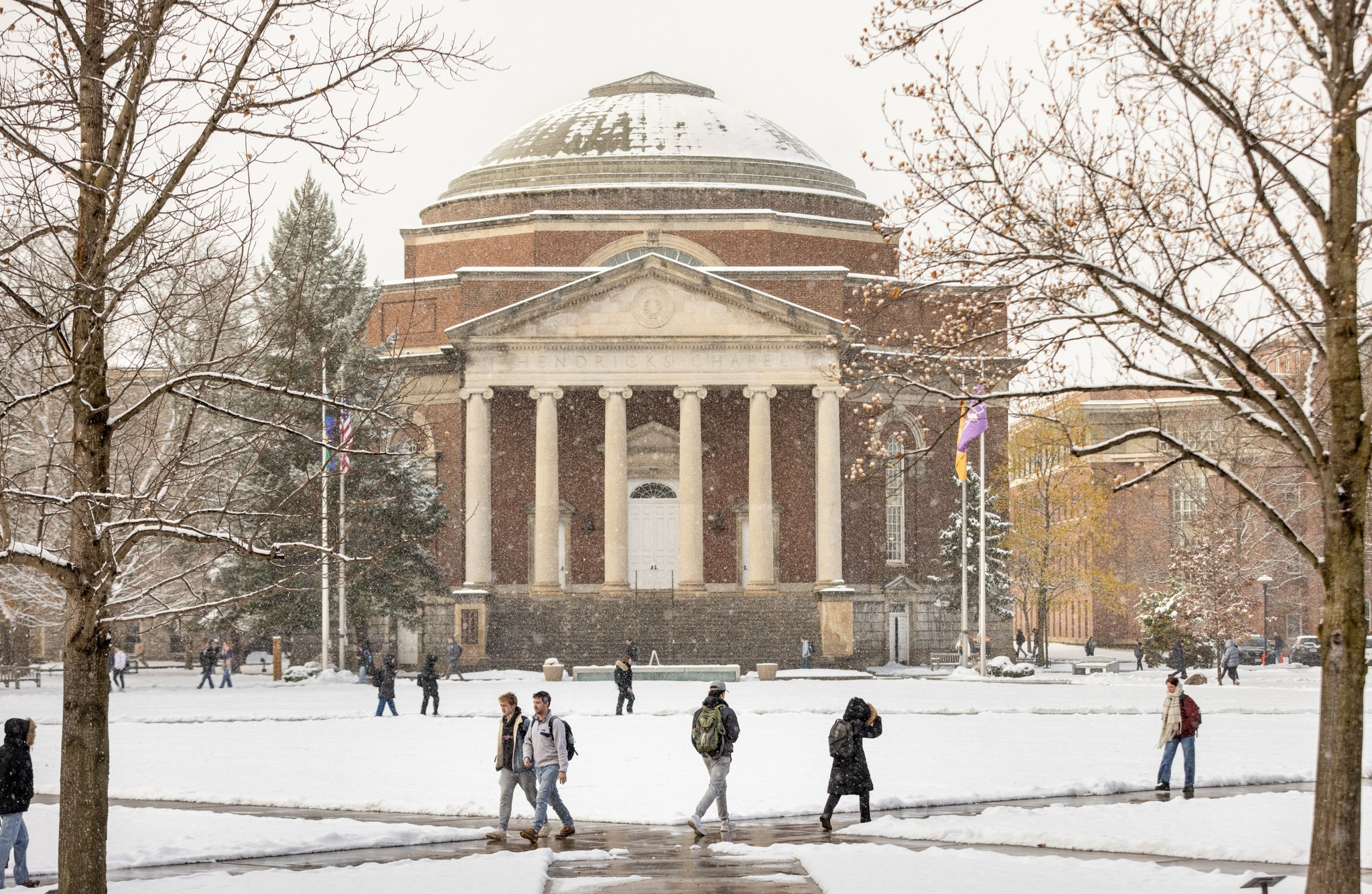 Students walking in front of the snow-covered Hendricks Chapel on a winter day.