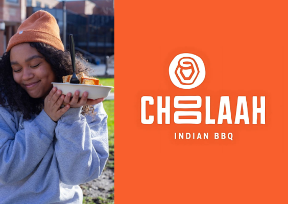 A student holds up a bowl of Indian barbeque food.