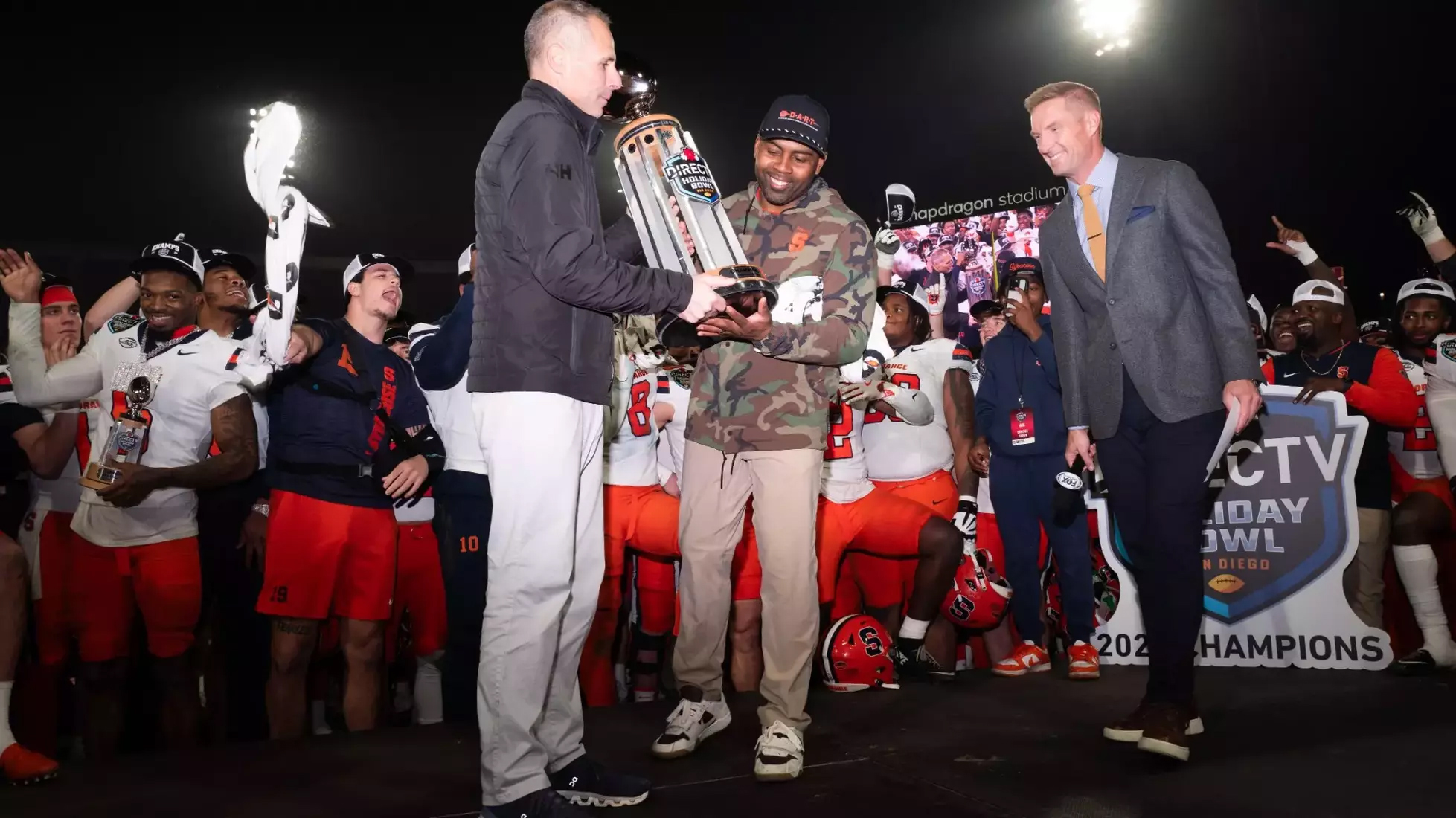 person handing another person a trophy in front of a crowd