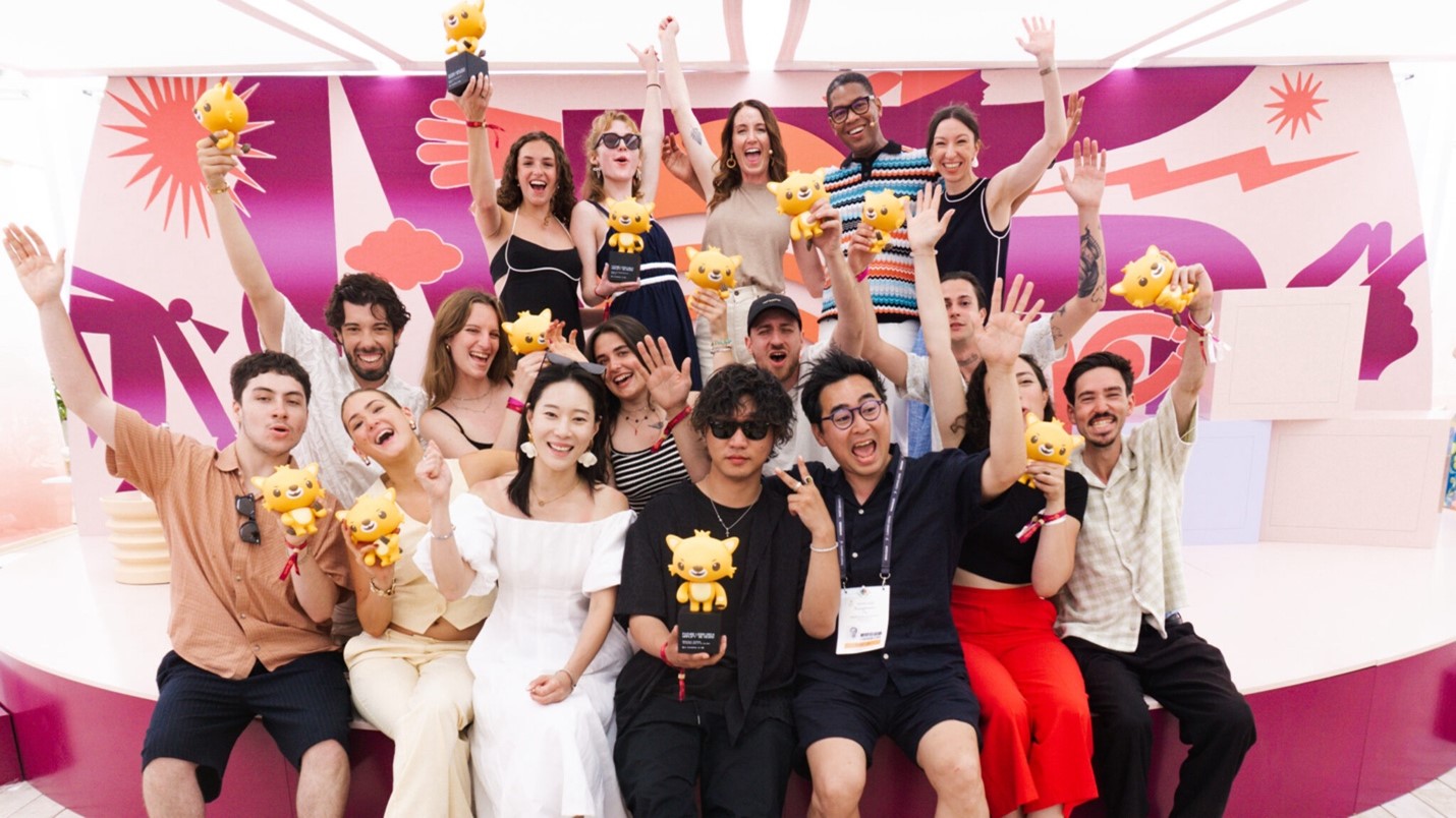 group of people sitting and standing on a stage and many holding trophies