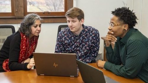 three people disscussing a topic around their computers