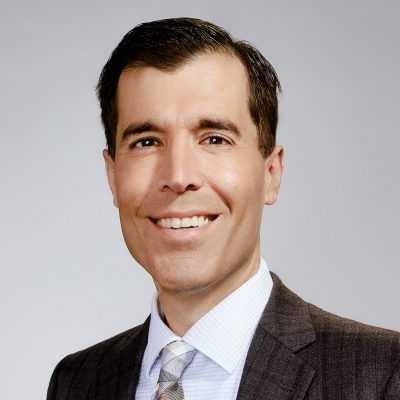 A man smiles while posing for a headshot.