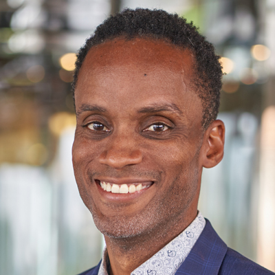 A man smiles while posing for a headshot.