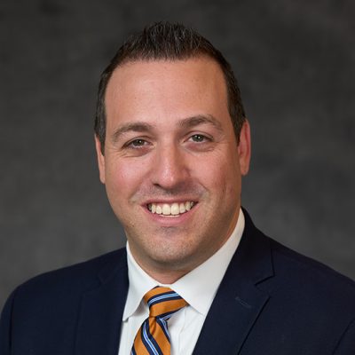 A man smiles while posing for a headshot.