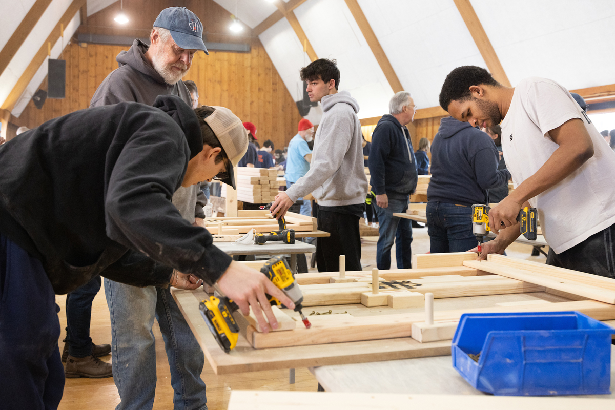 Student volunteers drill boards during the build