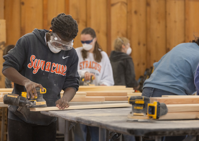 A student sands a board during the bed build