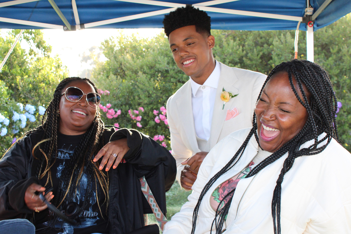 Two writers pose with an actor on the set of "Bel-Air."