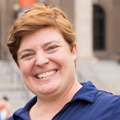 A person smiles for a headshot while on the campus of Syracuse University.