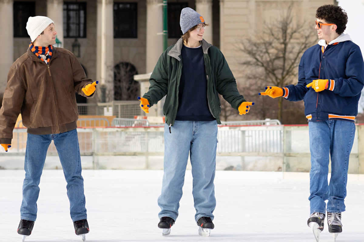 Three students talk while ice skating in downtown Syracuse.