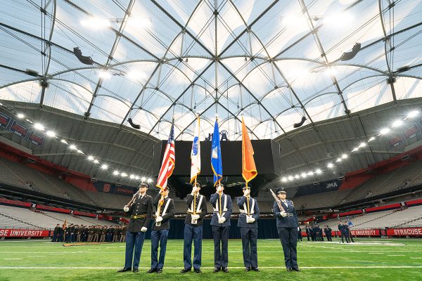 military cadets standing in a line and holding flags inside a stadium