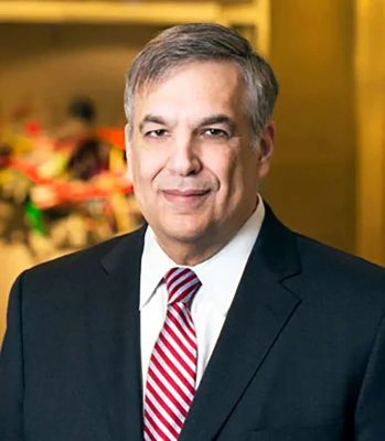 Person in dark suit, white shirt, and red striped tie with a blurred colorful background