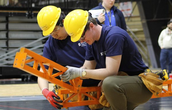 Students with hard hats on participate in the 2025 ASCE Steel Bridge competition