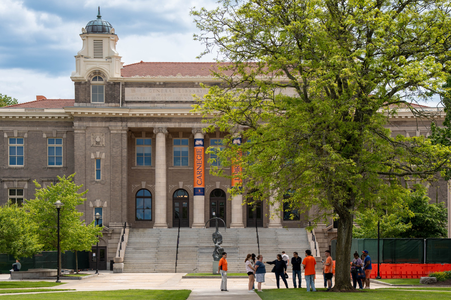 A campus tour stops in front of Carnegie Library on a spring day