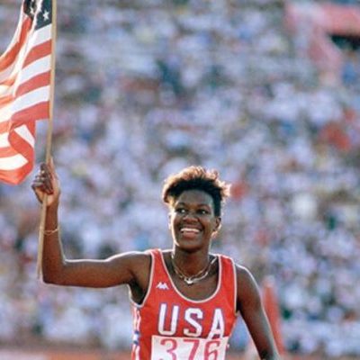 runner in the Olympics carries an American flag in front of spectators