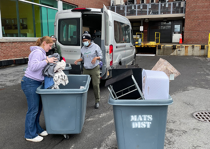 people loading items from bins into a van