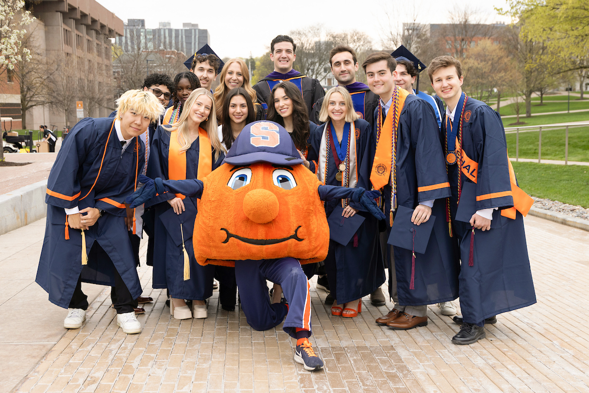 group of people in academic regalia posing on Einhorn Family Walk with Otto
