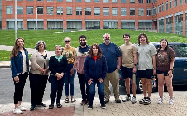 group of people posing on a sidewalk with a building in the background