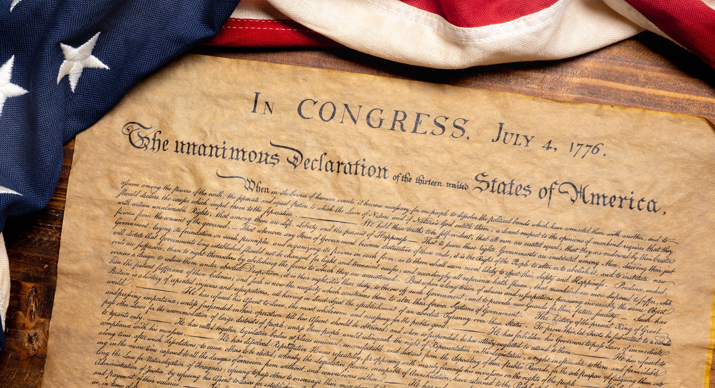 Version of Declaration of Independence written on parchment paper surrounded by American flag