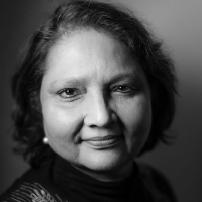 A black and white photograph of a person with medium-length hair. The background is plain and out of focus.