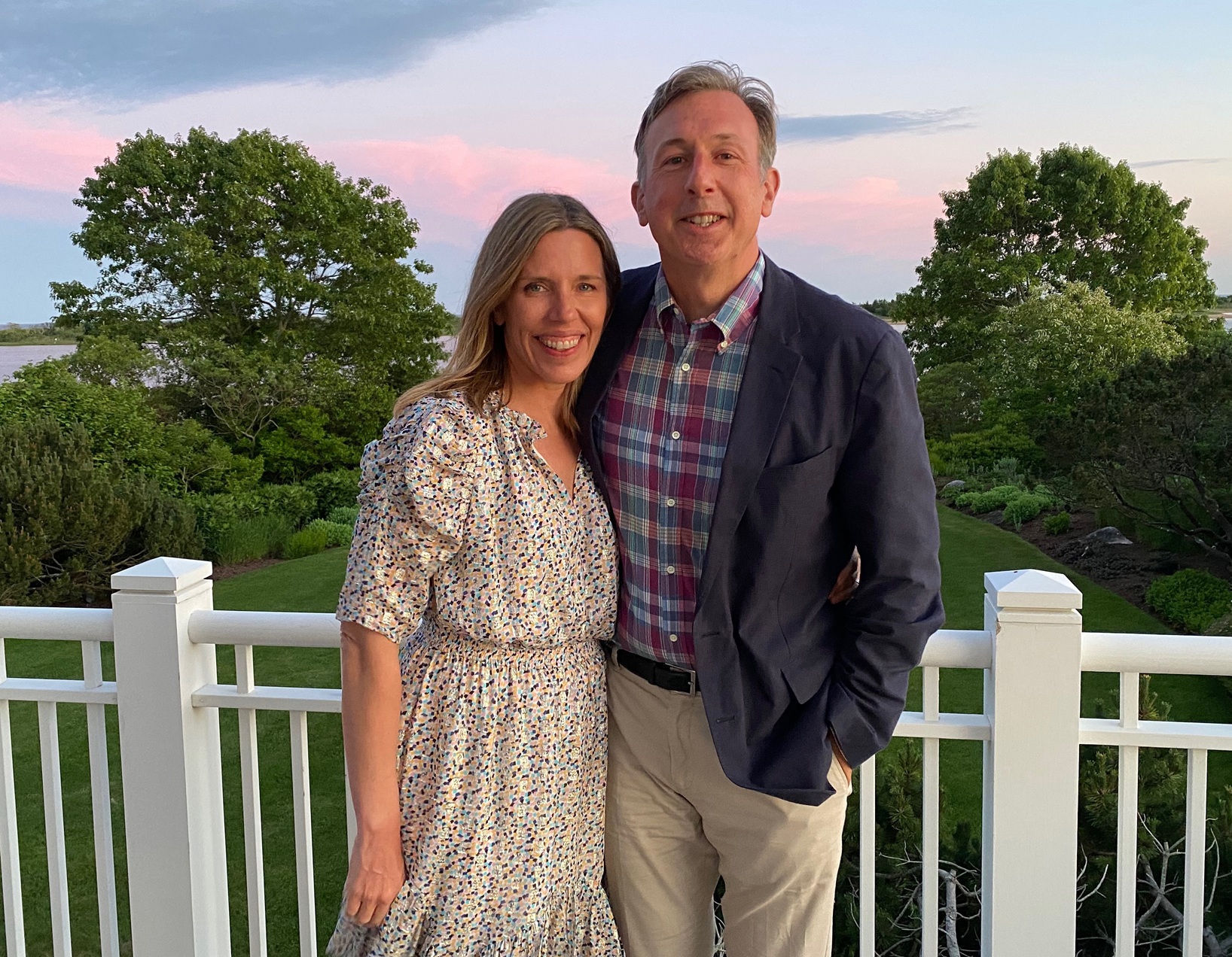 two people standing in front of a railing above a grouping of trees