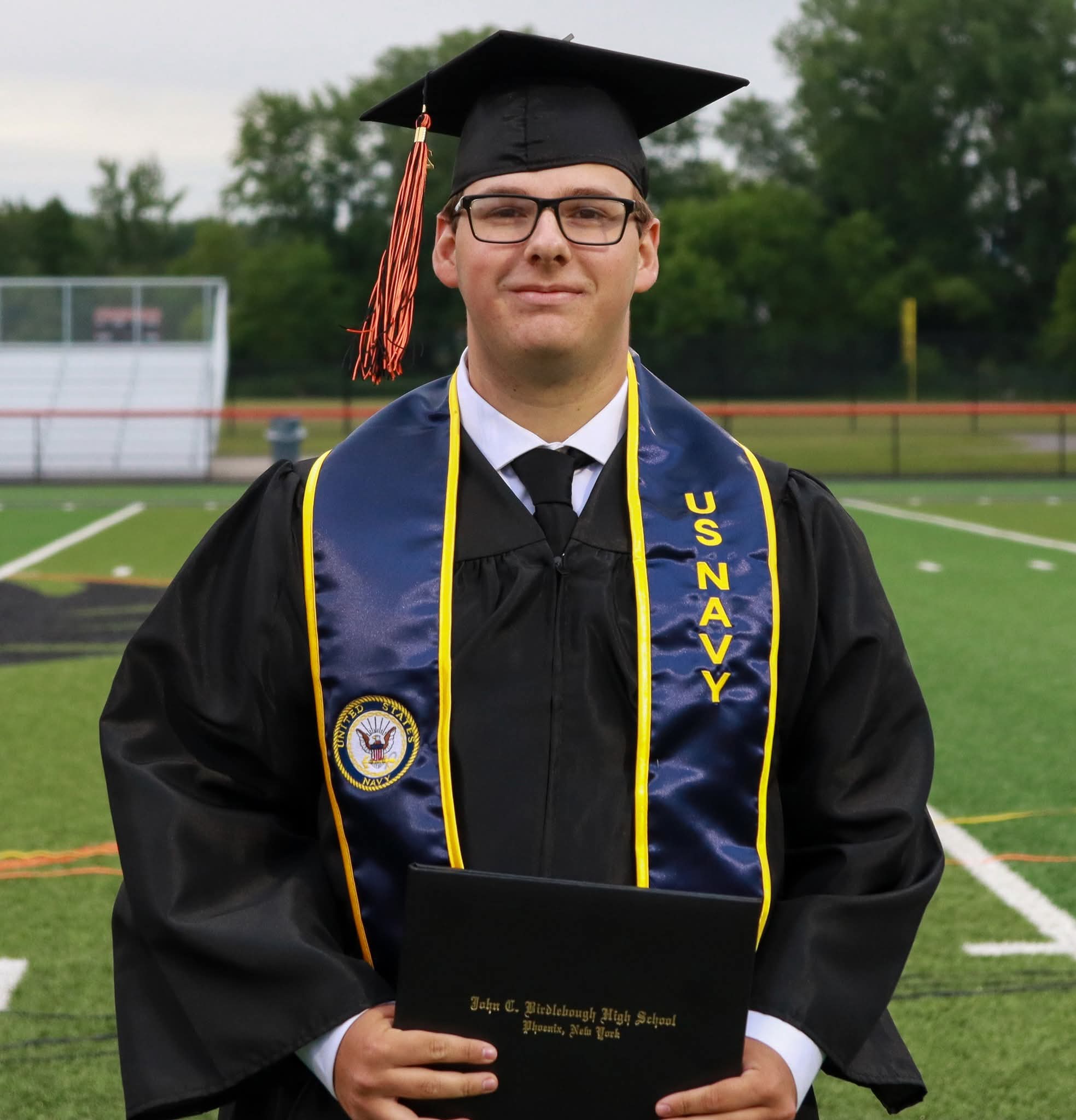 Cameron Besaw in graduation cap and gown with a sash that says U.S. Navy