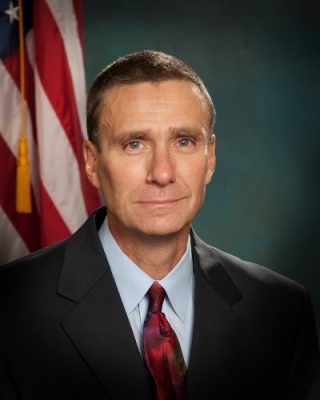 Man in suit with an American flag in the background