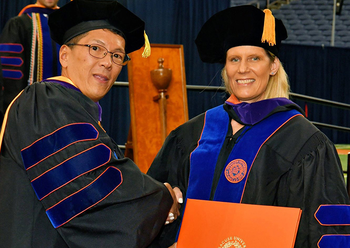two people in graduation robes shaking hands