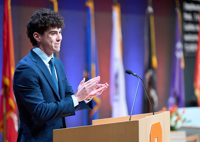 person standing at a podium clapping
