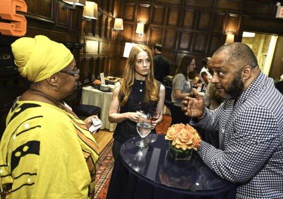 Three people have a lively conversation at an after-event reception