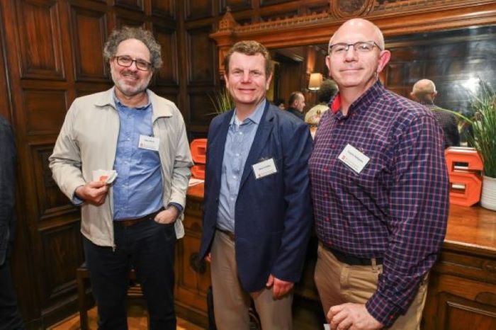 Three people at an event face the camera, smiling