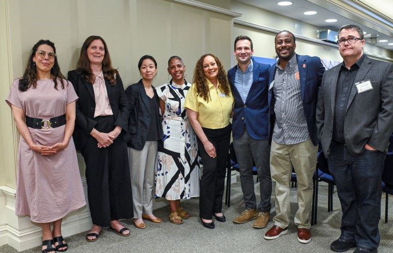 A group of eight faculty presenters poses and smiles