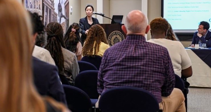 person at lectern addresses a group of event attendees