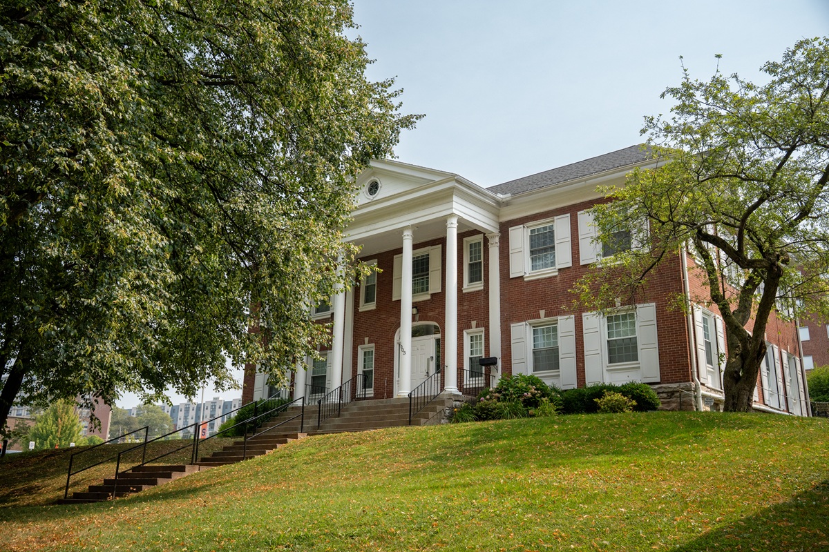 large, two-story brick building with white columns and trim, featuring a central entrance with steps leading up to it