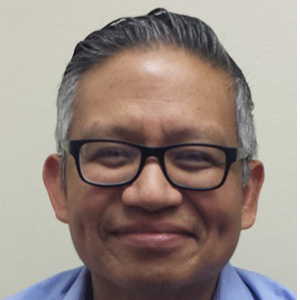 Man wearing blue shirt and glasses and smiling