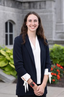 Woman wearing white blouse and blue jacket standing in front of the Hall of Languages