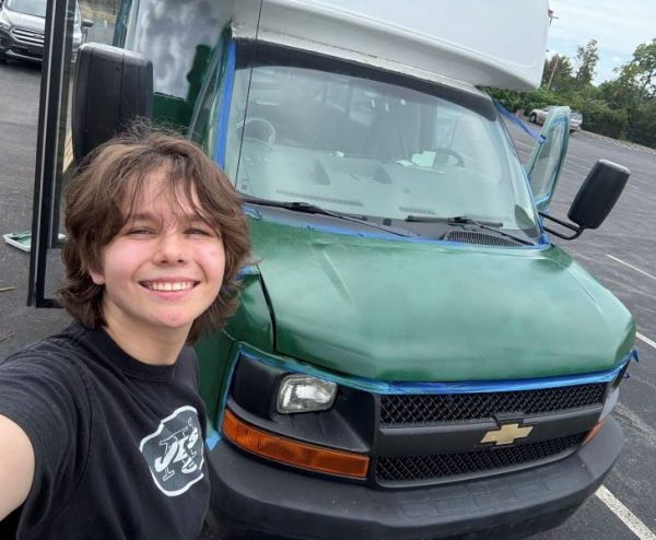 A person standing beside a green Chevrolet truck with a black grille