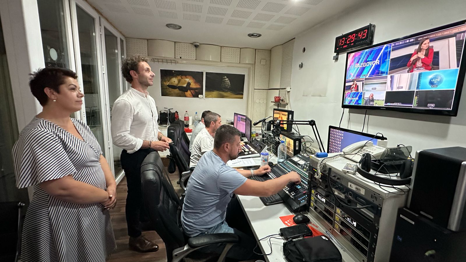 People standing and seated in a newsroom studio