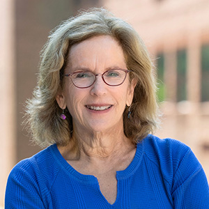 Miranda Spivack, woman smiling, wearing blue blouse and glasses