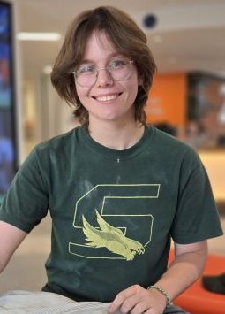 Person in green t-shirt designed with an 'S' and eagle graphic