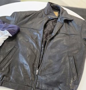 Black leather jacket with front zipper and two pockets with a quilted inner lining.