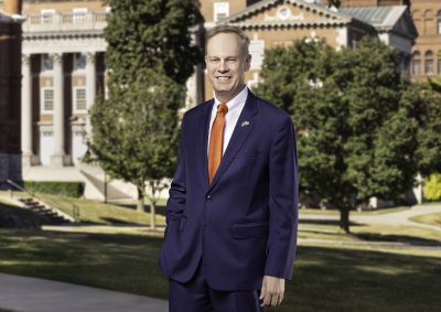 person standing on campus sidewalk with buildings in the background