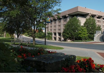 Exterior of Bird Library, a gray granite building. The Einhorn Walk runs in front of the building, and flowers are blooming along the path