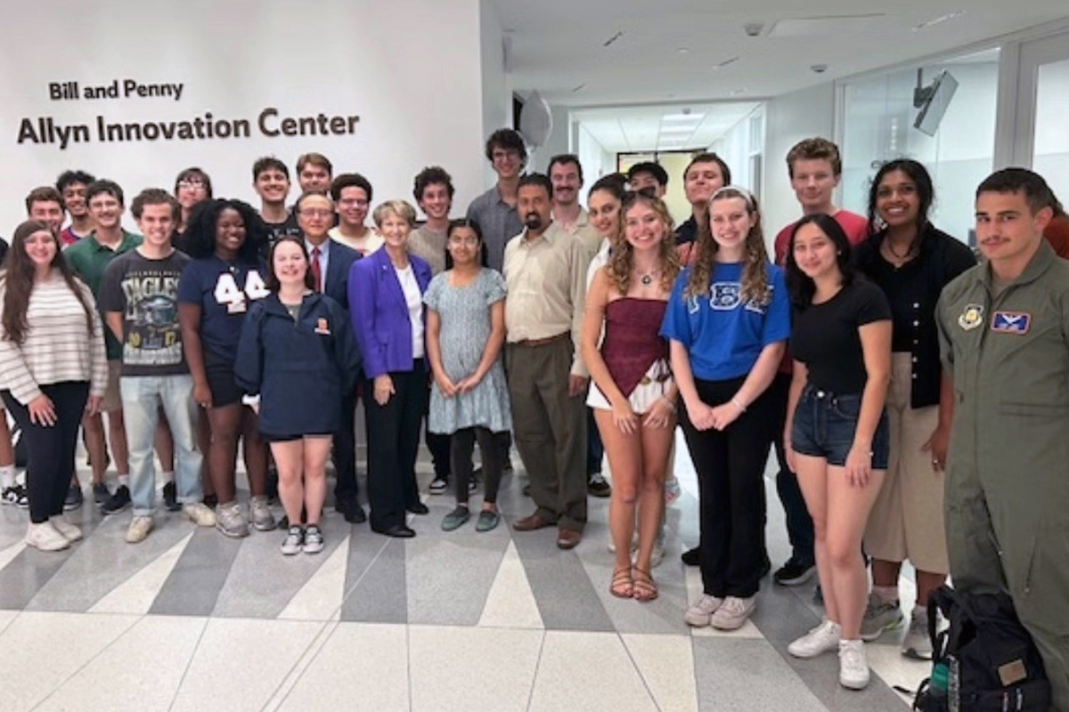 A large group of students and adults pose for a group photo in the lobby of the Bill and Penny Allyn Innovation Center, with the center's name visible on the wall behind them.
