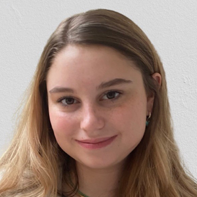 A student smiles while posing for a headshot in front of a white backdrop.