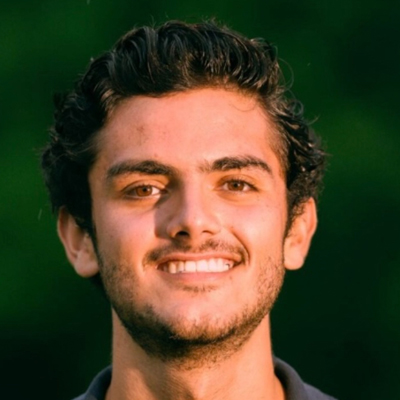 A student smiles while posing for a headshot outdoors.