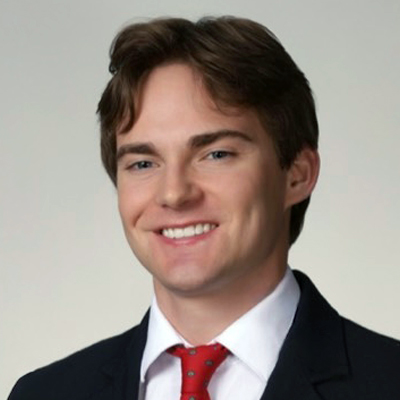A student smiles while posing for a headshot in front of a white backdrop.