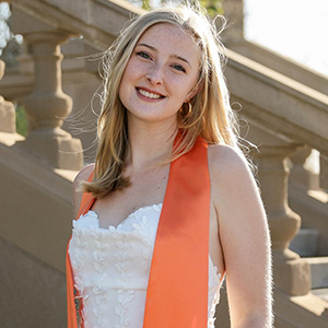 Young woman, smiling, in white dress with an orange sash