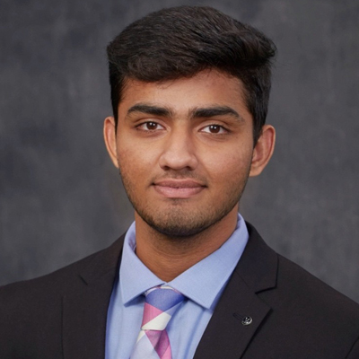 A student poses for a headshot in front of a grey background.