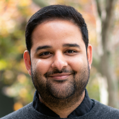 A person smiles while posing for a headshot outdoors.